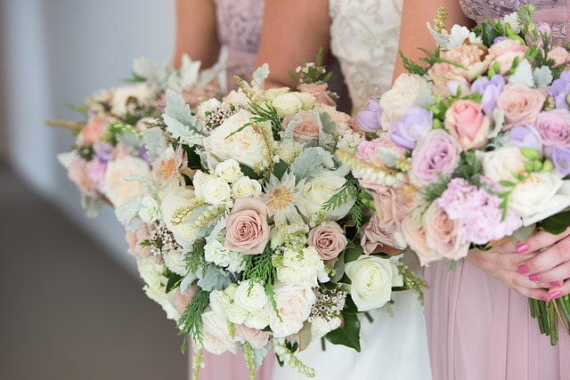Colorful pastel floral bouquets being held by three bridesmaids.
